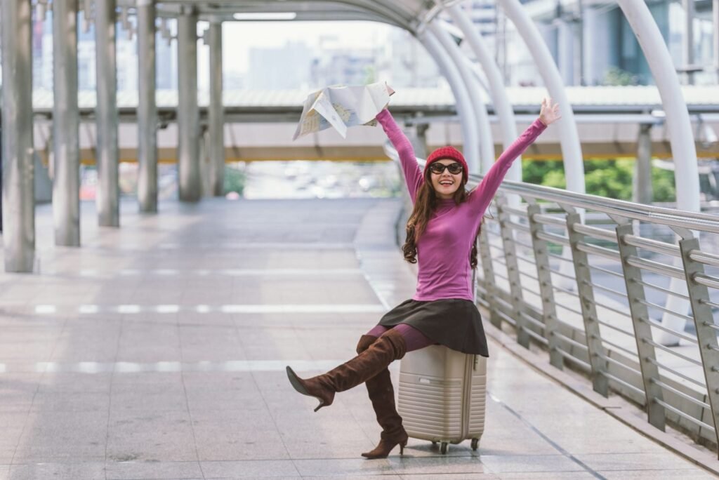 A solo traveler sitting on her suitcase by the road