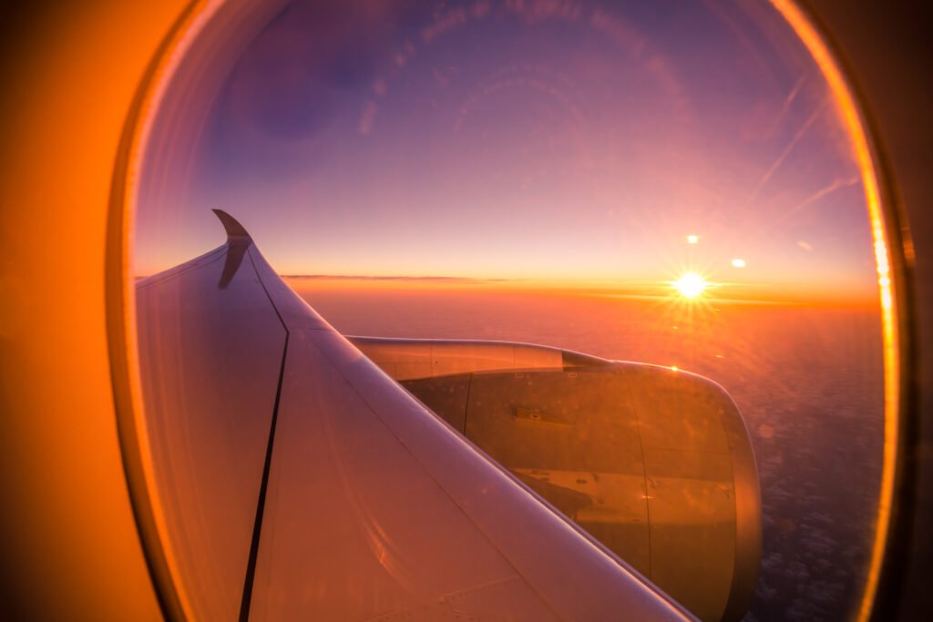 A scenic sunset view through an airplane window and wing during flight