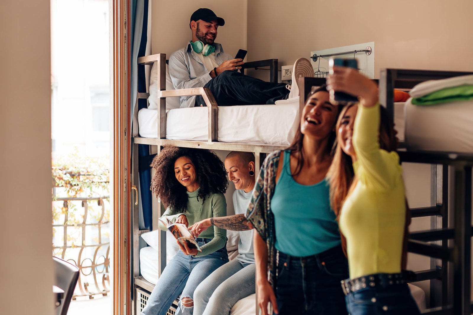 Young backpackers relaxing in a hostel room with bunk beds