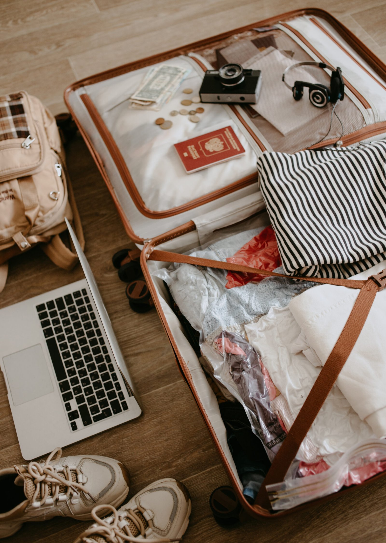 Open baggage with laptop, headphones, passport, and camera