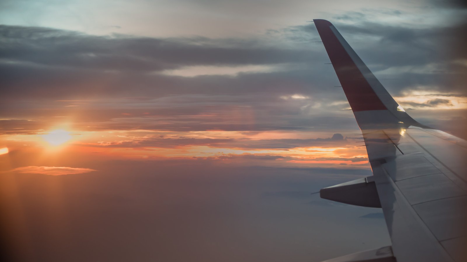 Airplane window view with wing at sunrise