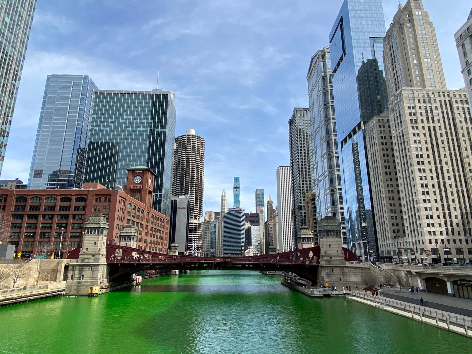 A green bridge over the Chicago River surrounded by downtown buildings
