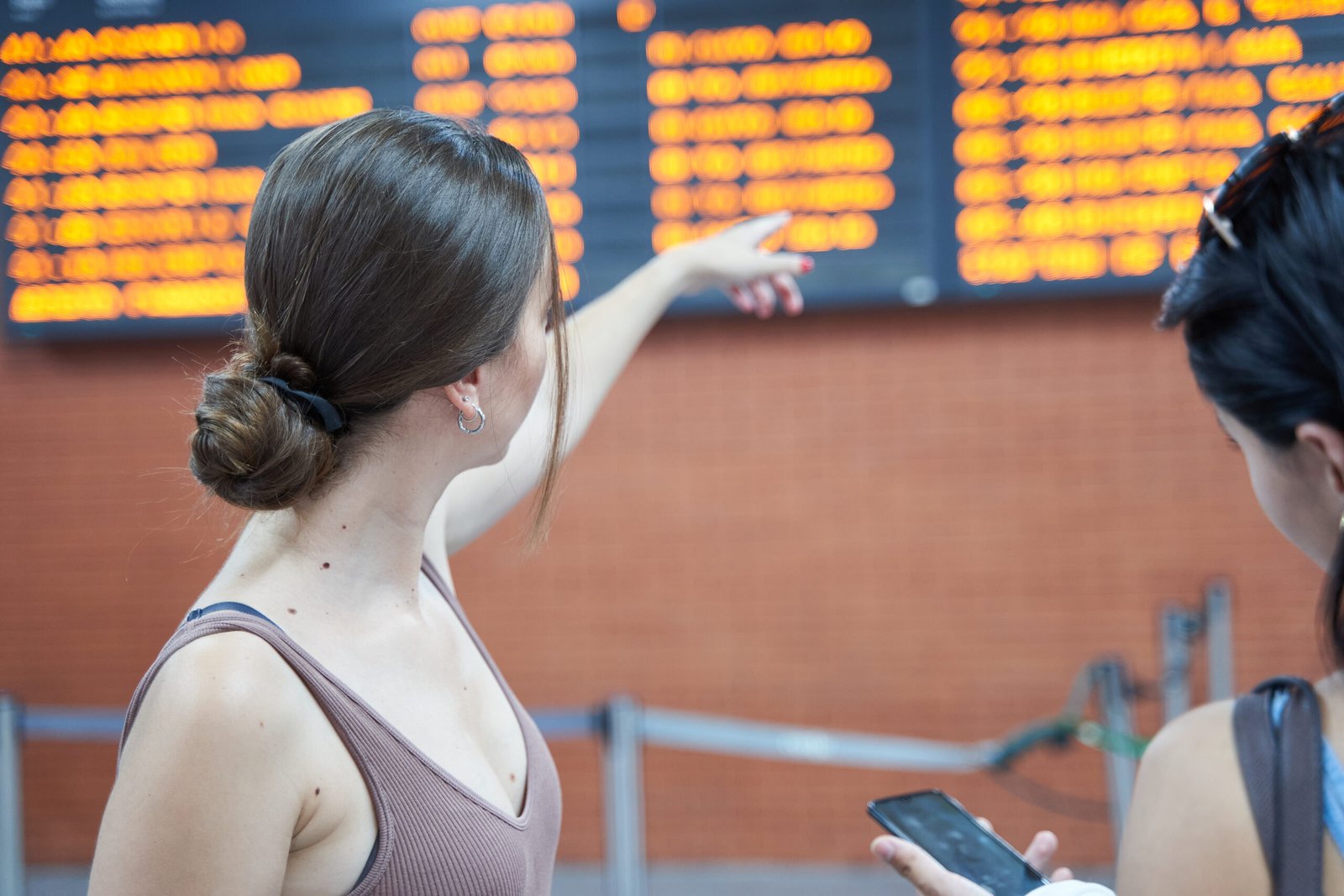 A couple checking a flight information board and smartphone at the airport