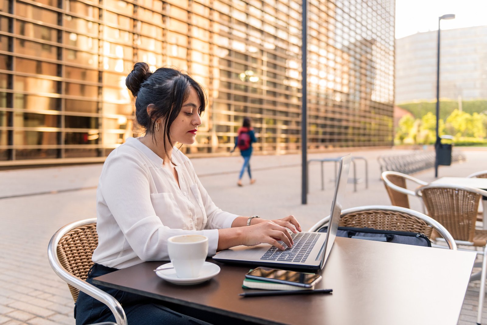 Businesswoman working with laptop on terrace of city coffee shop