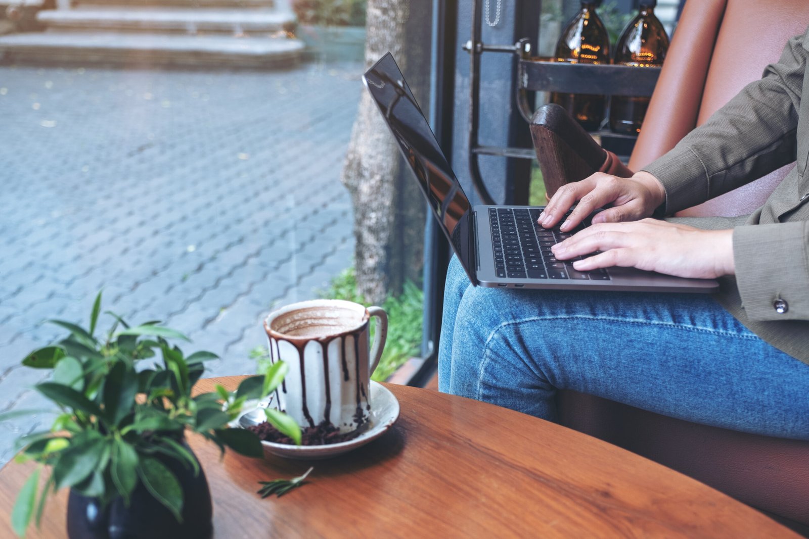 A remote worker typing on a laptop keyboard while sitting in a cafe