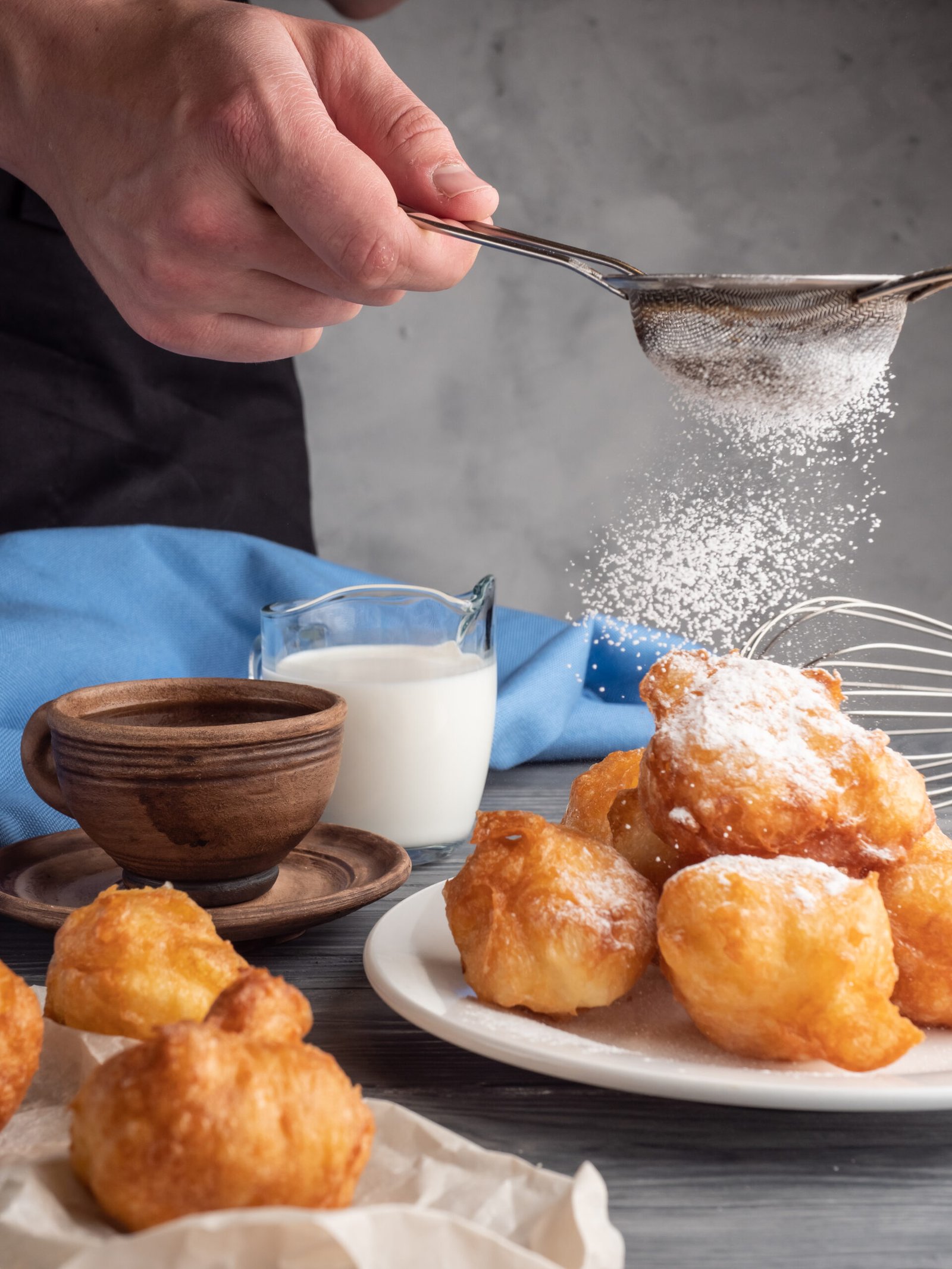 Beignet sprinkled with powdered sugar next to coffee