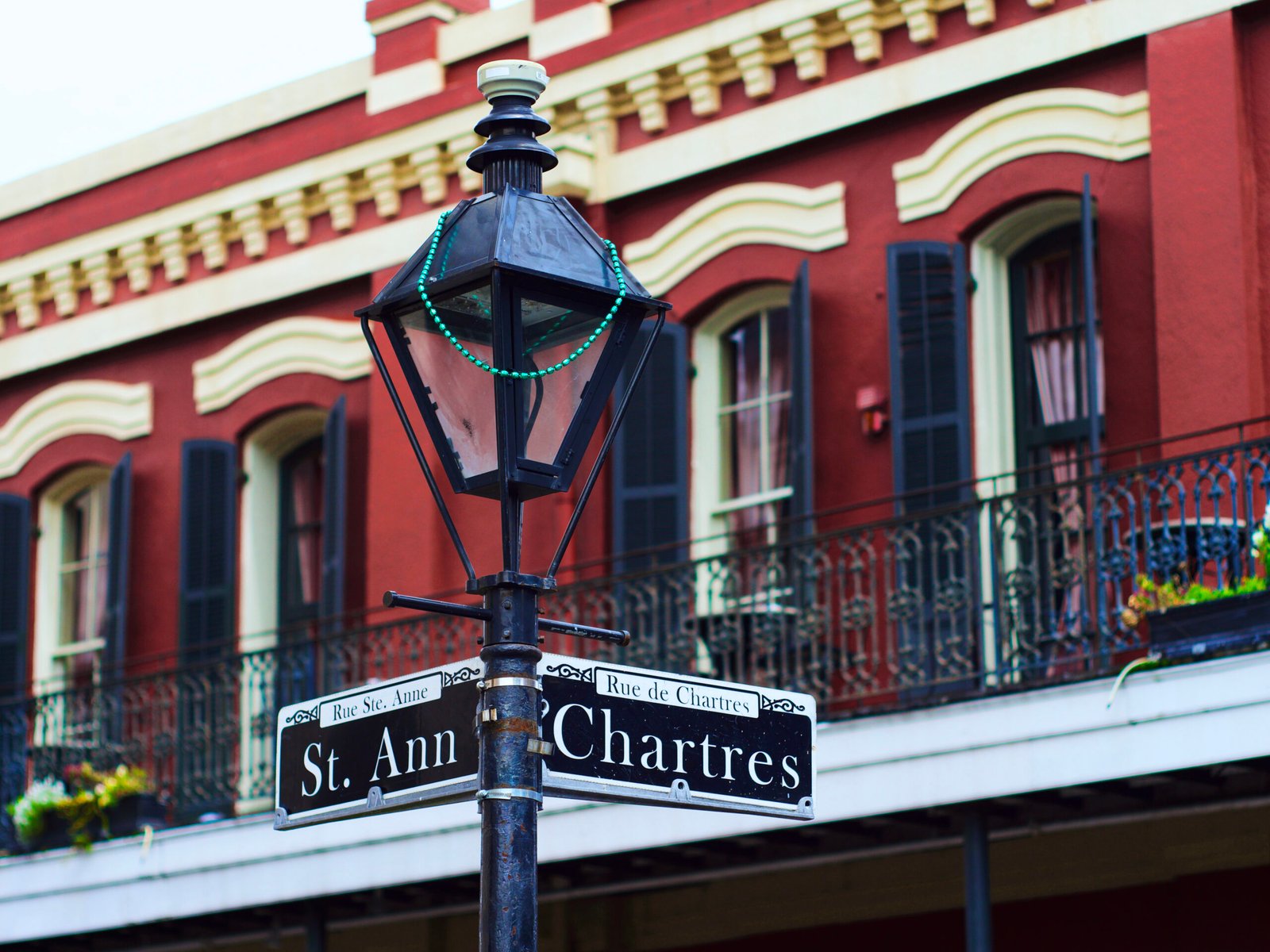 A French Quarter street sign in New Orleans against a historic red building
