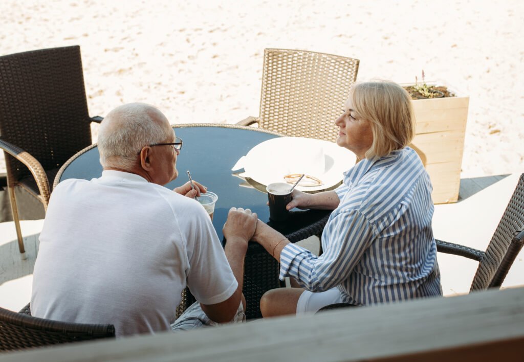 An elderly couple enjoying drinks at a seaside cafe in Spain