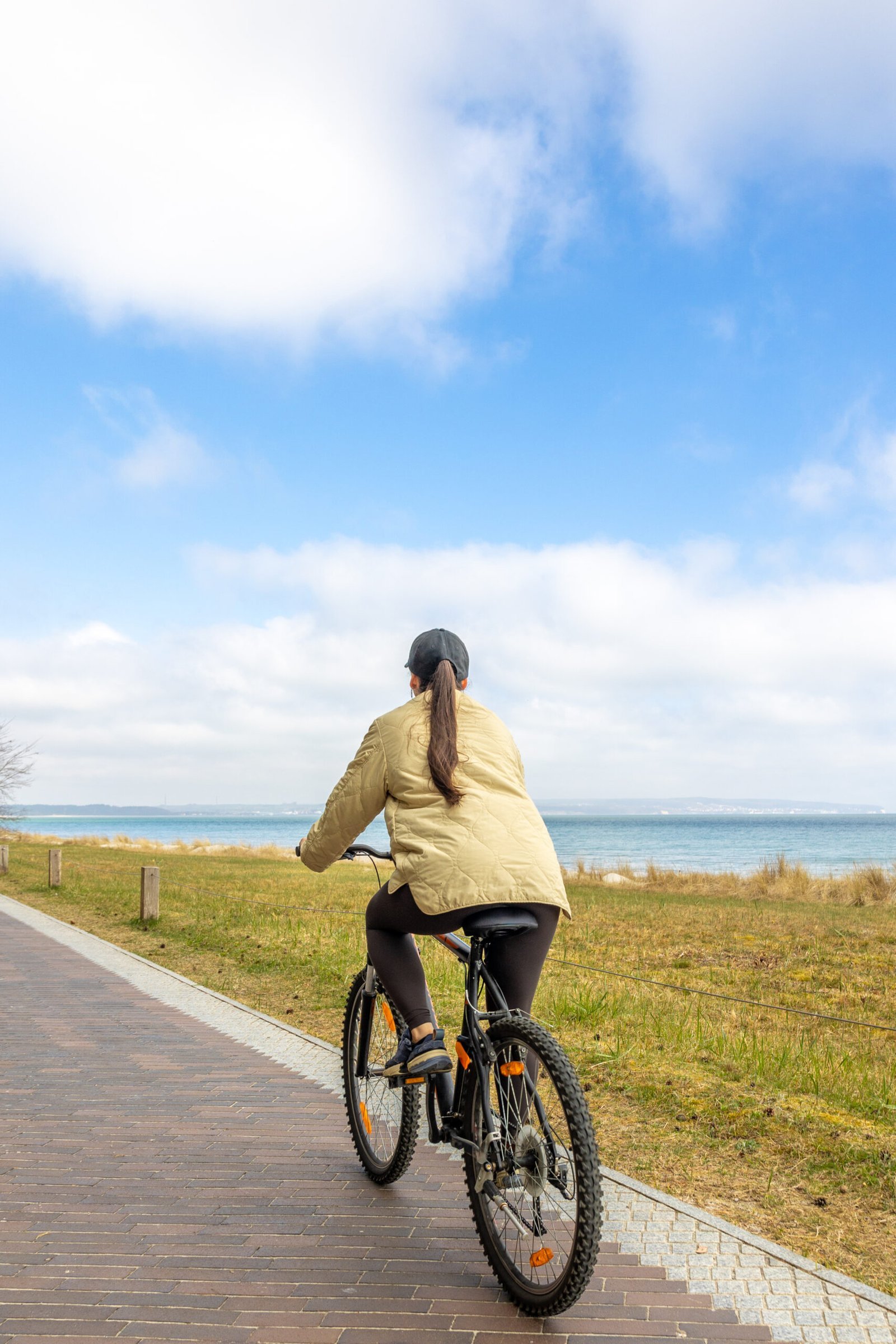 Woman cycling toward the sea on a California coastal bike path near Santa Monica