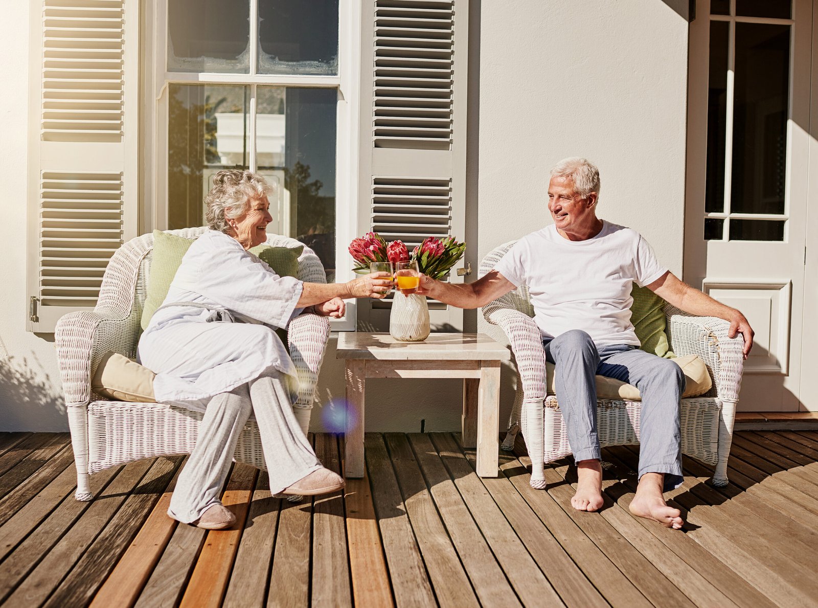 A happy senior couple toasting with drinks on a sunny patio at home