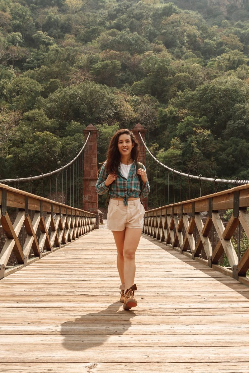 A confident solo traveler smiling on a bridge