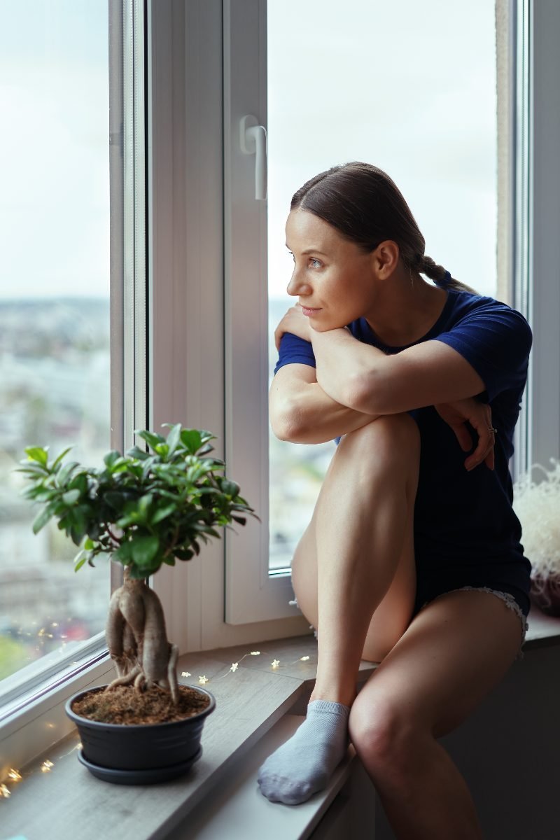 A nervous traveler looking out a window before a trip
