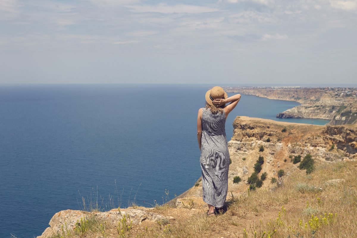 A solo female traveler at a clifftop ocean view