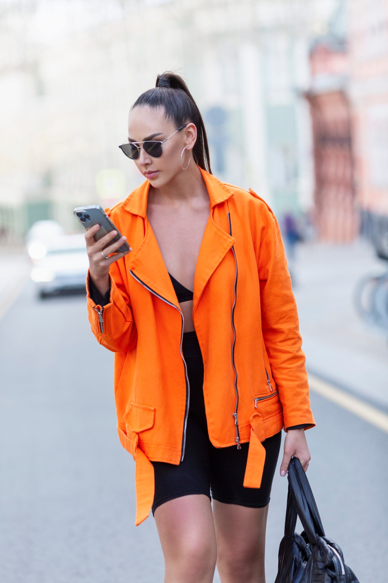 Stylish woman with phone on a city street