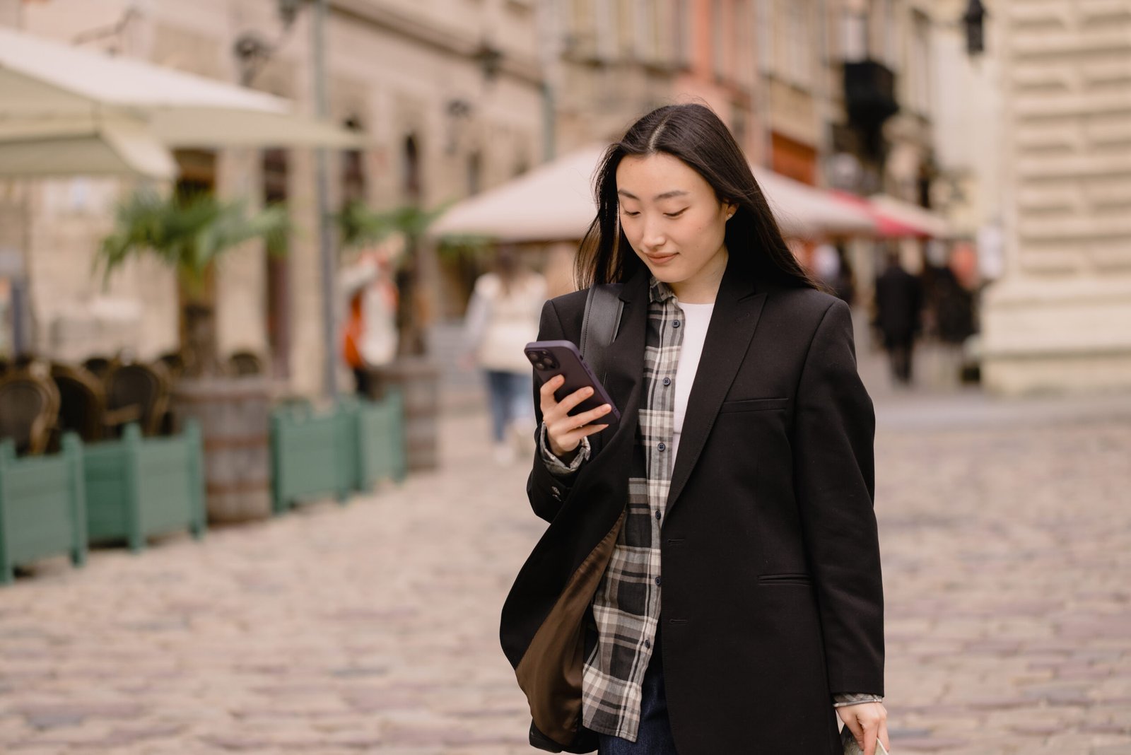 A solo female tourist checking directions with a smartphone in a European old city street