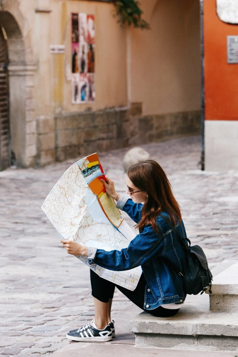 A solo traveler looking at a map on some steps