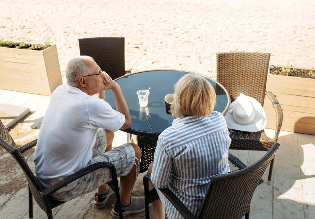 Elderly couple sitting at an outdoor cafe near the sea in Spain