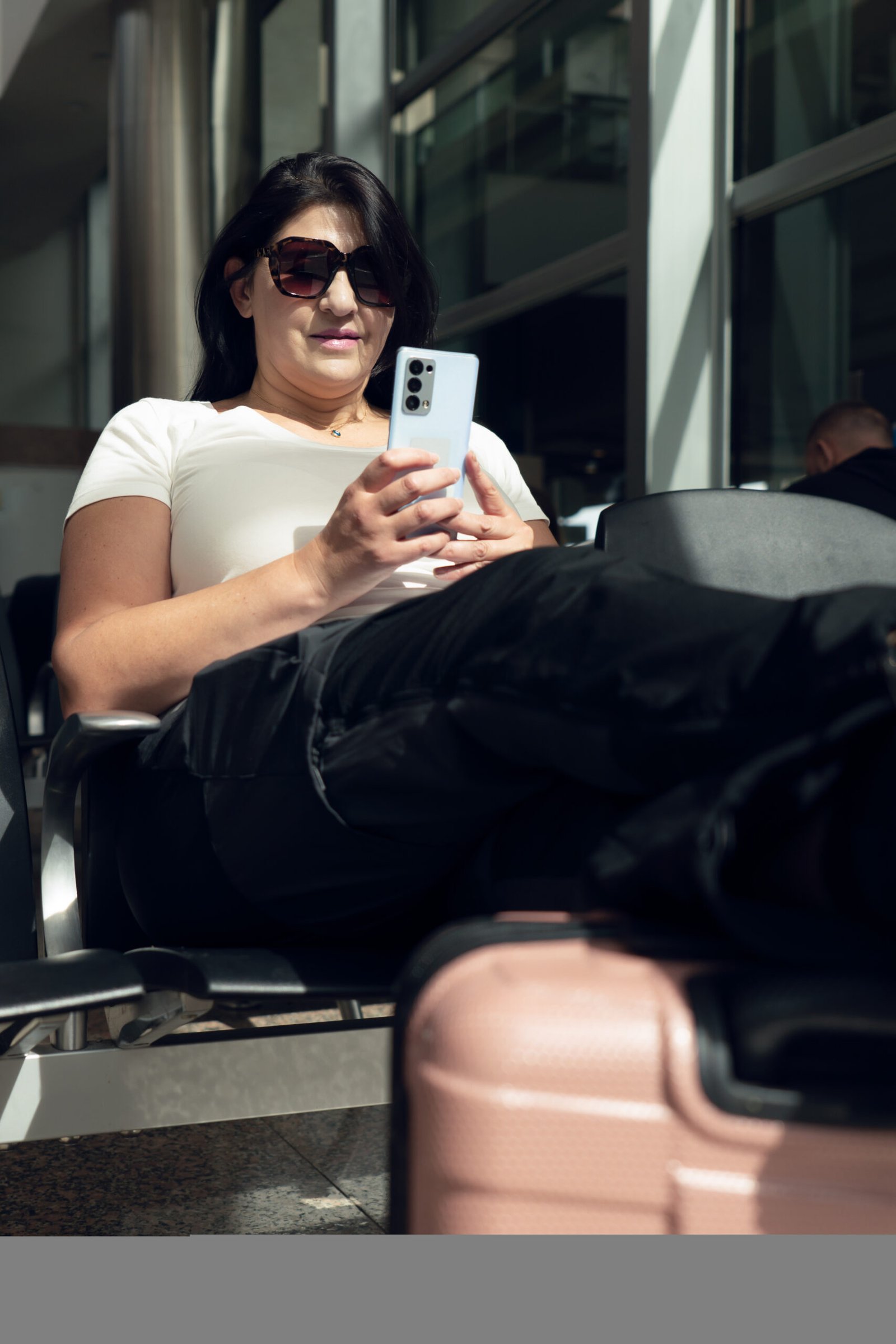 A traveler waiting at the airport while using a smartphone