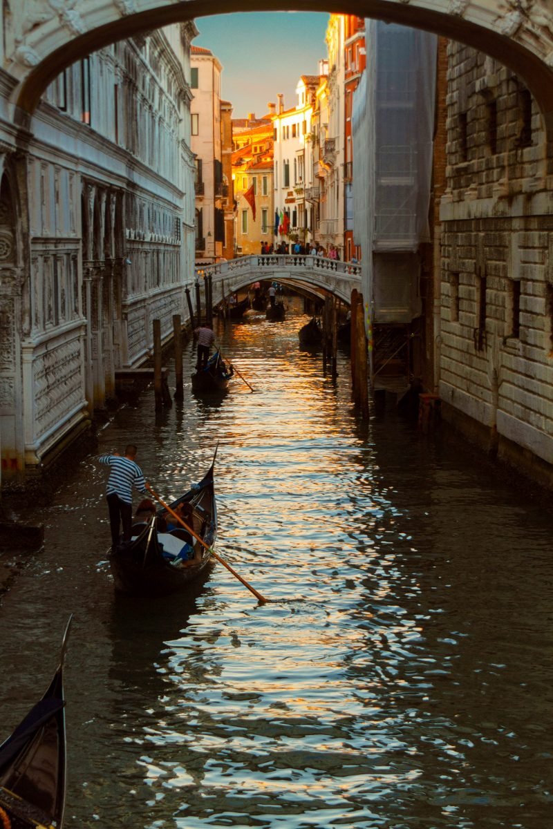 Gondolas along a narrow Venetian canal at sunset