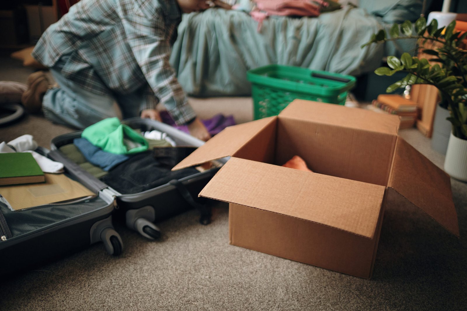 A young woman packing a suitcase and cardboard box for relocation