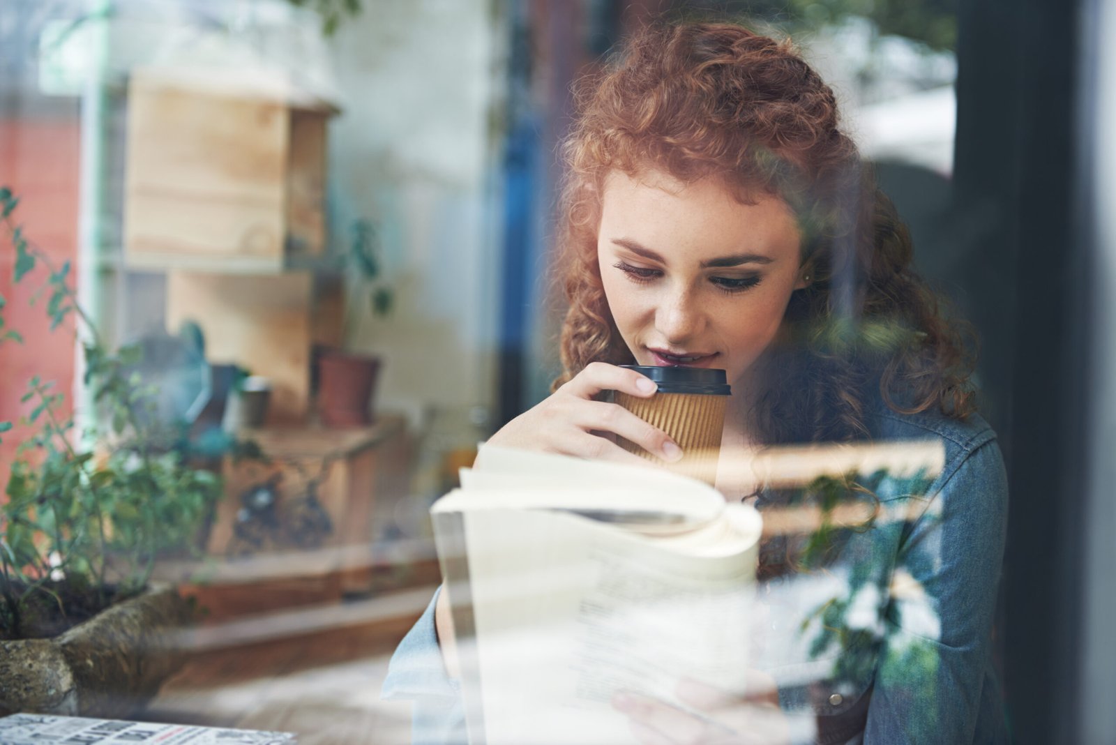 Woman reading book alone while drinking coffee at cafe