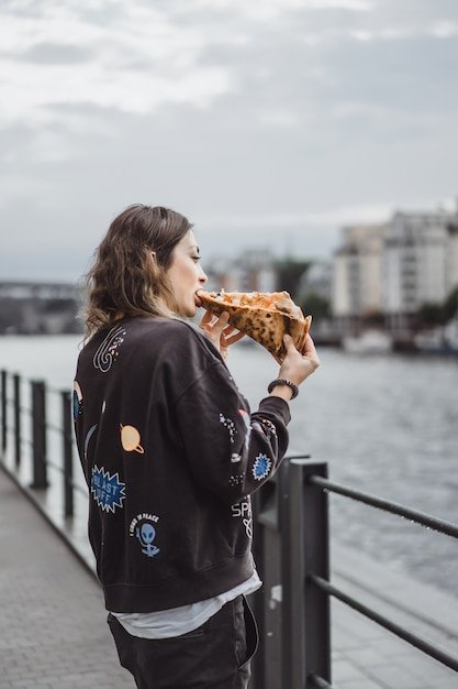 Person eating a New York pizza slice on the street