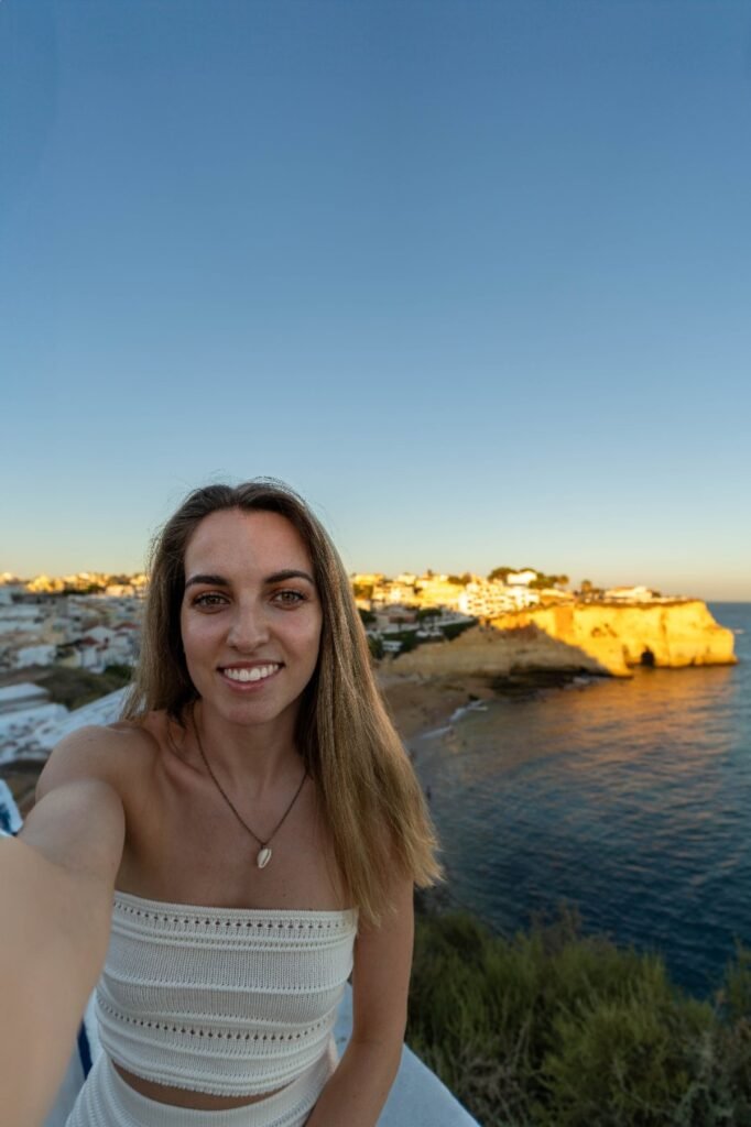 A solo traveller photographing herself above a coastal town