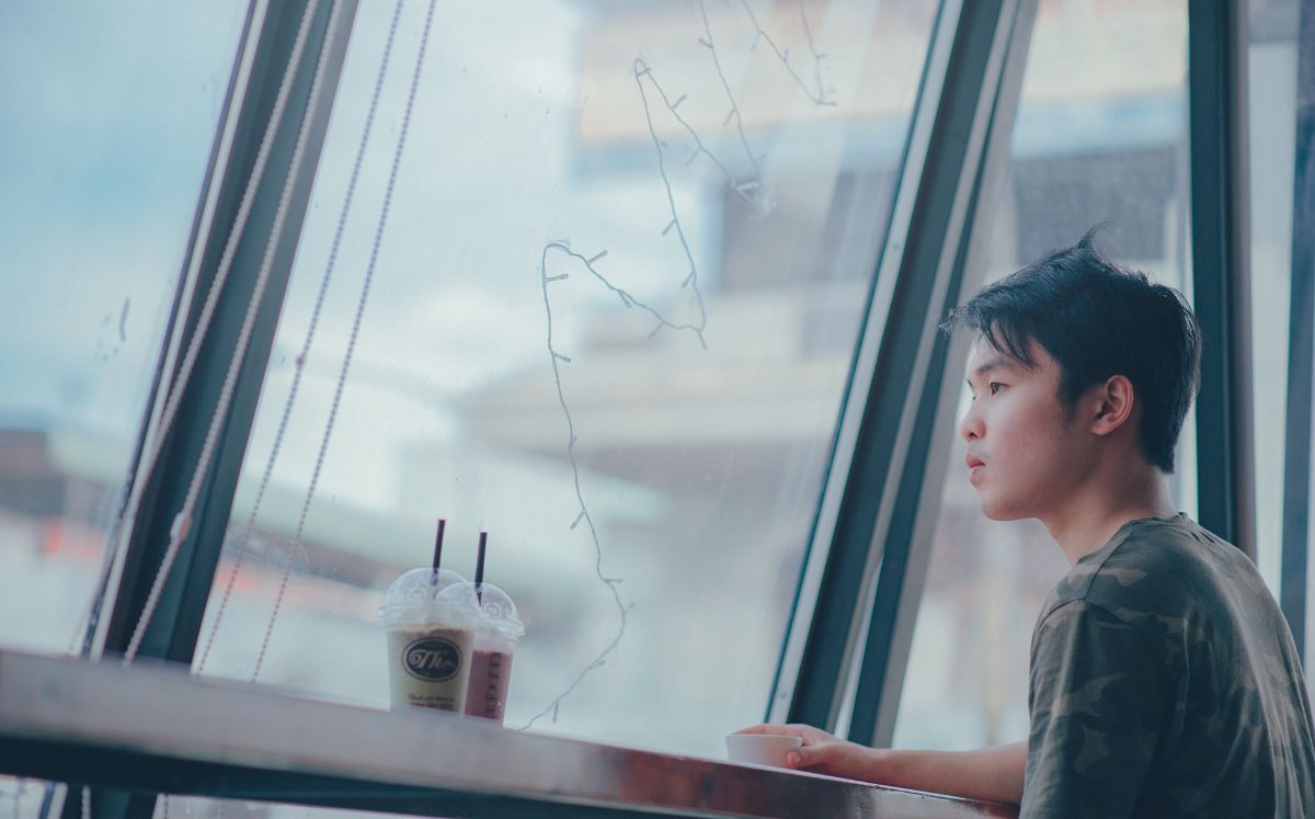Someone sitting alone in a cafe by a window