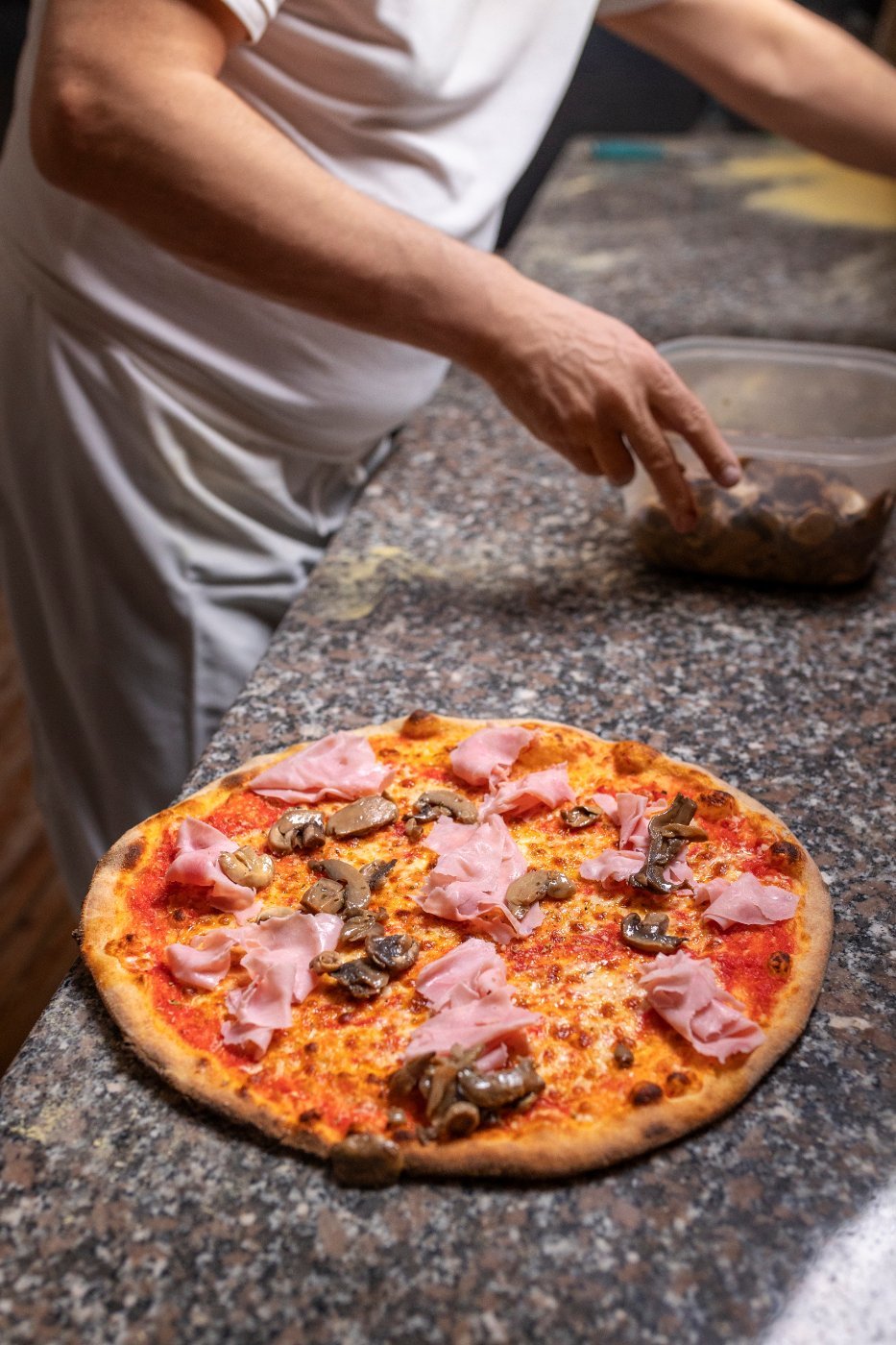 A pizzaiolo working the dough by hand