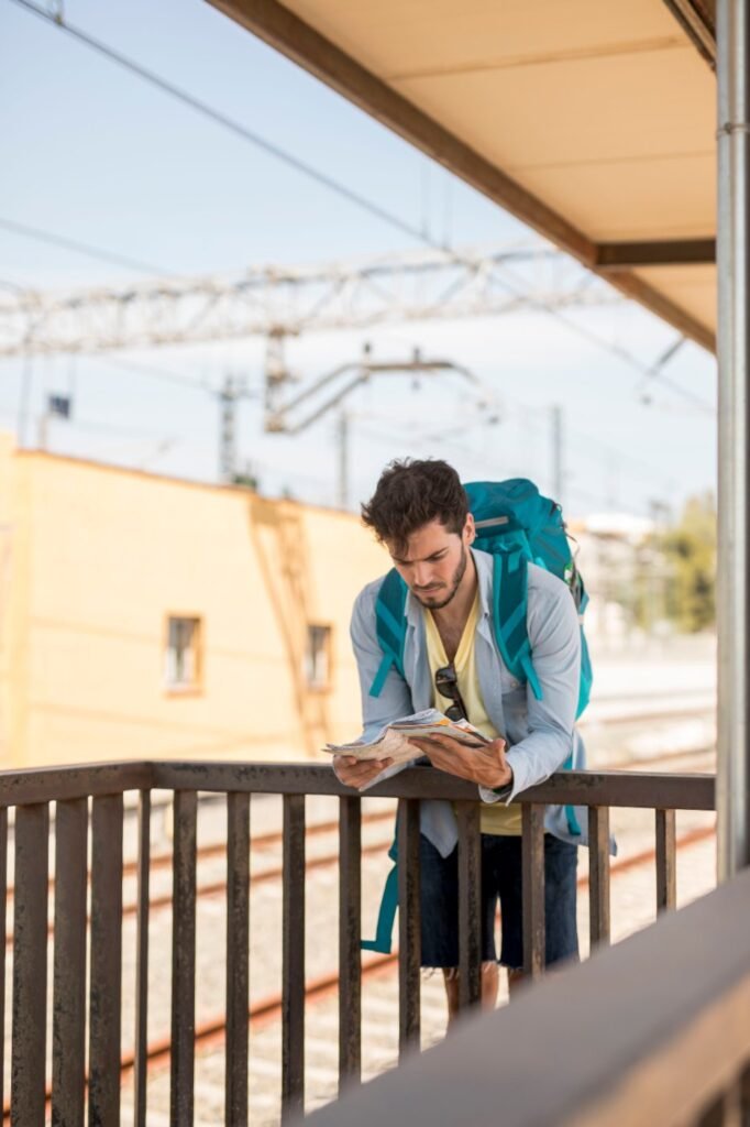 A solo traveller with a backpack leaning against a fence