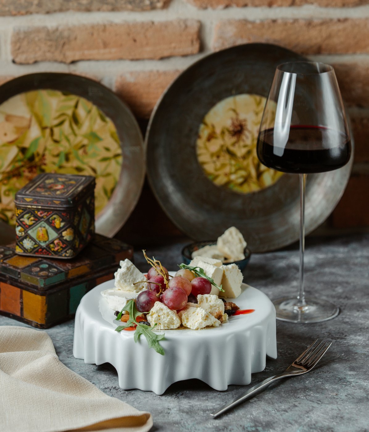 A cheese platter with grapes and a glass of red wine