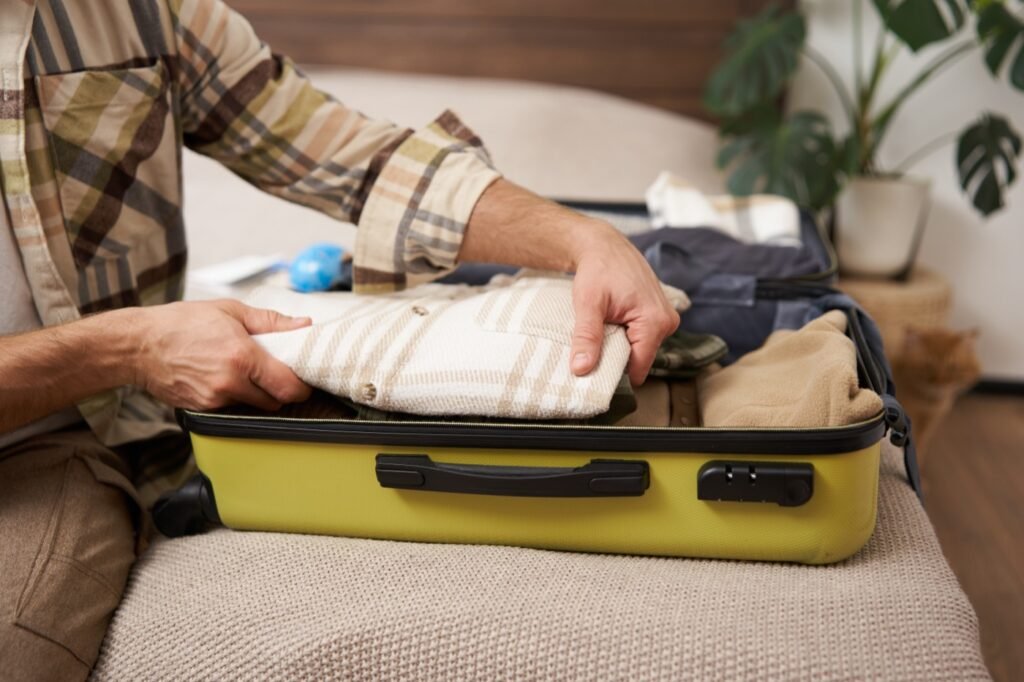 Hands packing clothes into a suitcase before a trip