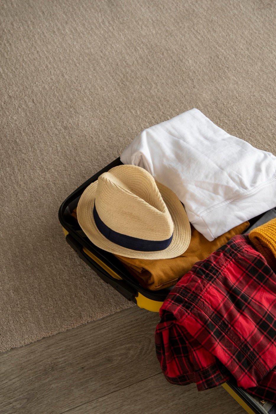 A suitcase mid-pack with clothes folded beside it
