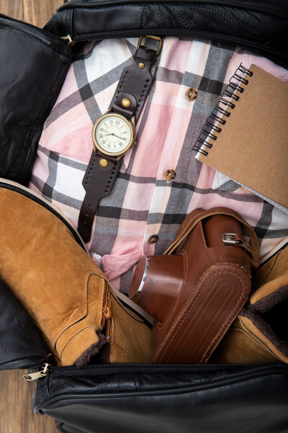 A travel bag packed with shoes and a camera