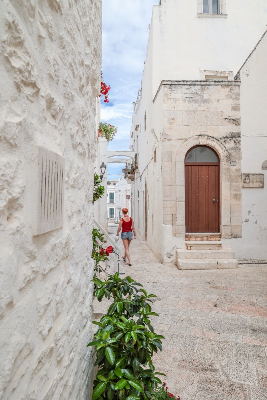 Walking a narrow white street in a southern Italian town