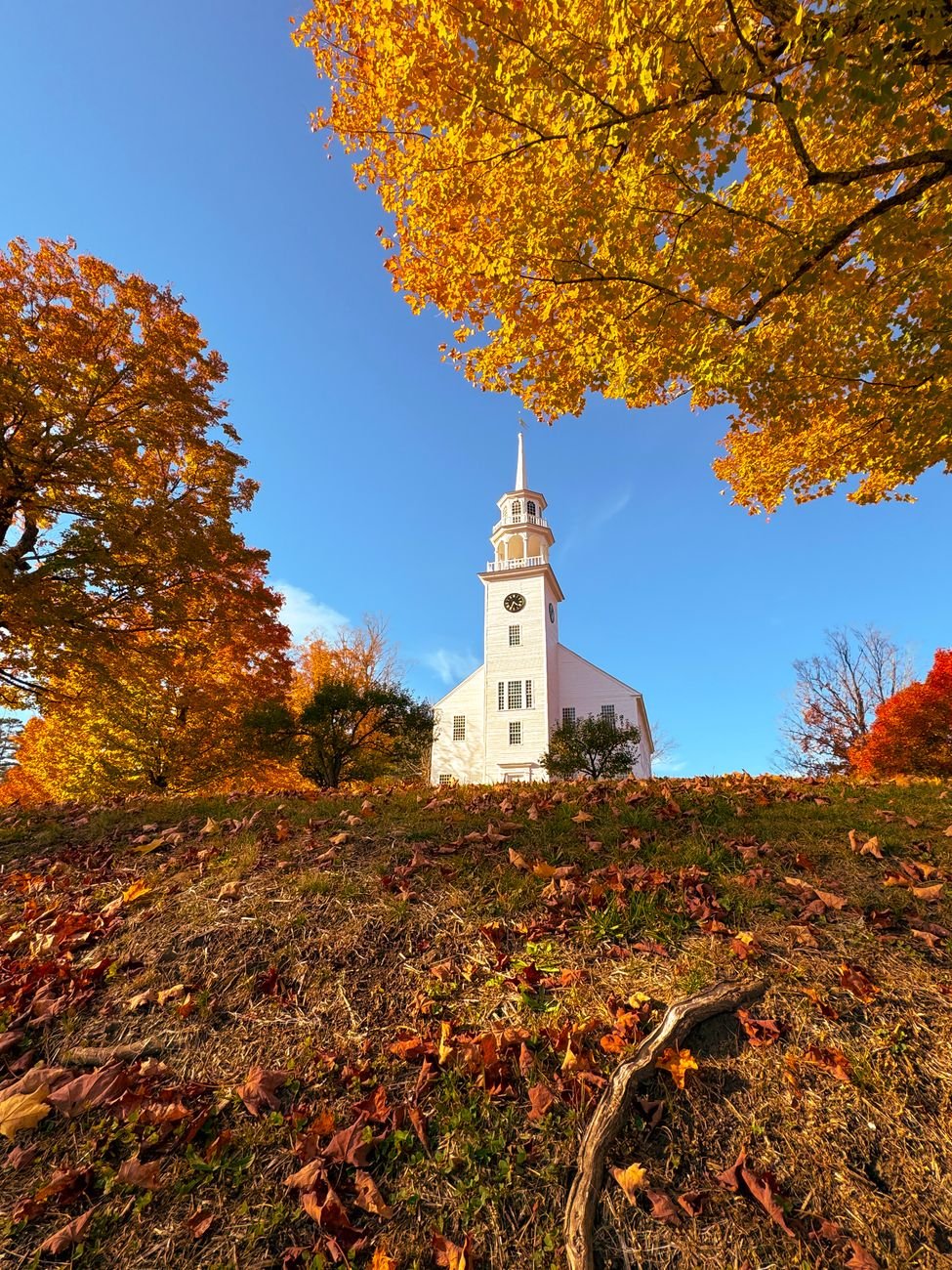 A white church and red maples on a Vermont back road in October