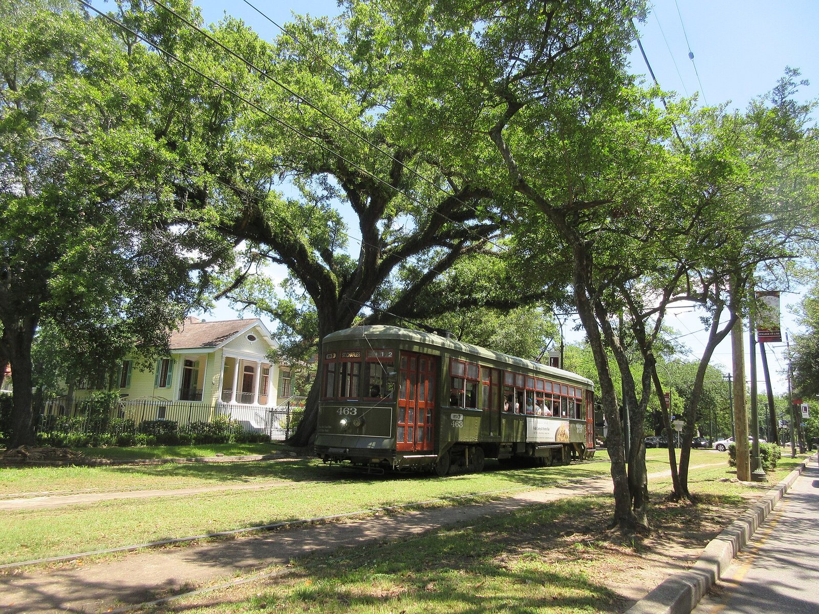 A green St. Charles streetcar under the oak trees