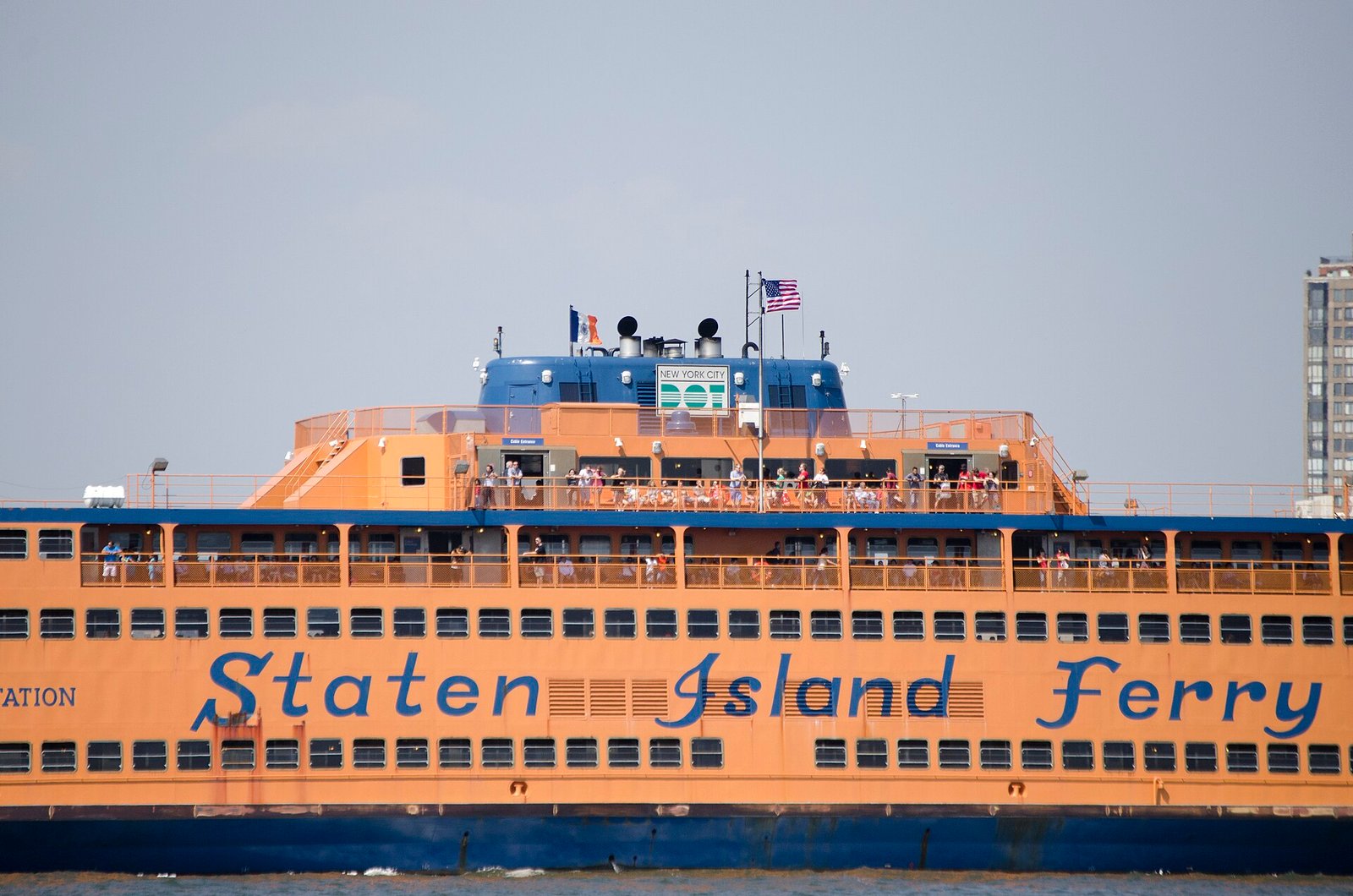 An orange Staten Island Ferry crossing New York Harbor